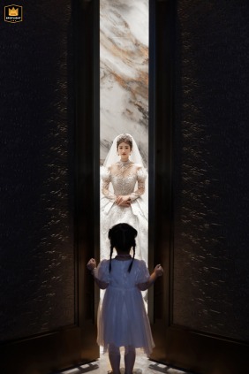 A documentary photograph at a hotel in Fujian, China, captures a touching scene. The image shows a little girl imagining herself in a wedding dress as the bride recalls her childhood.